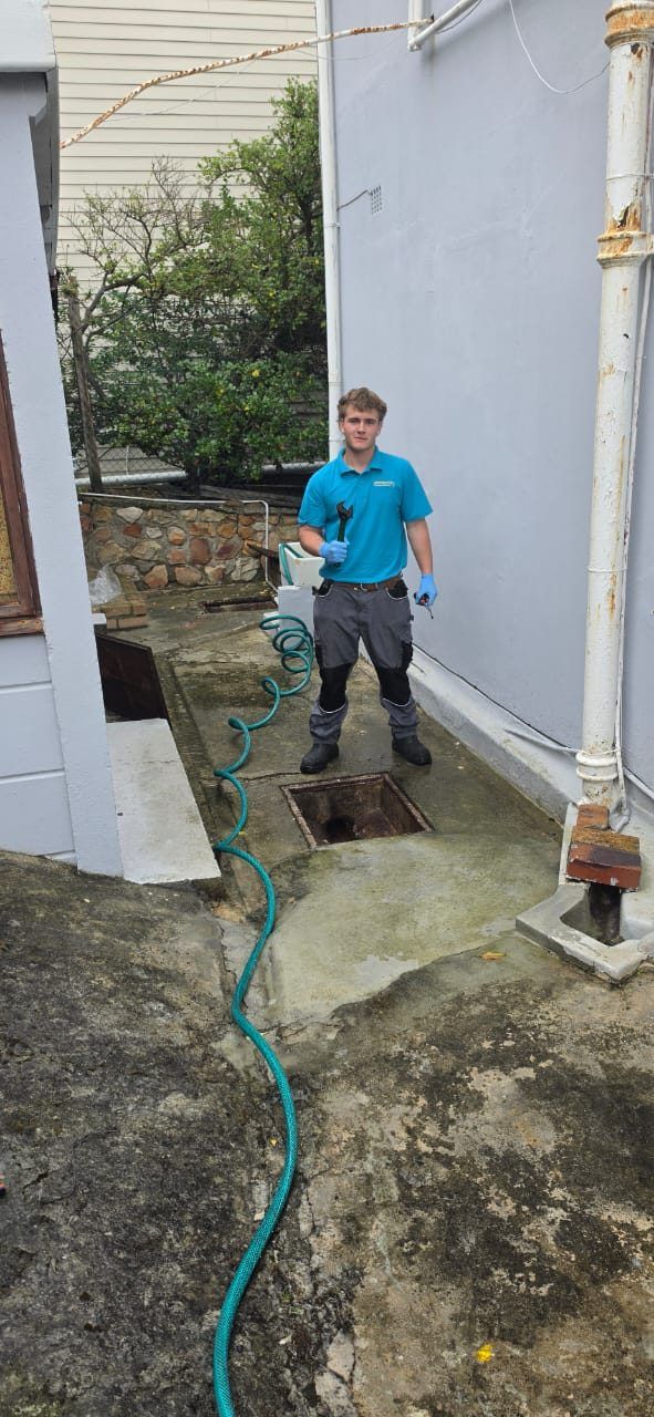 Lightning Fast plumber beside the opened inspection chamber after clearing the main drain